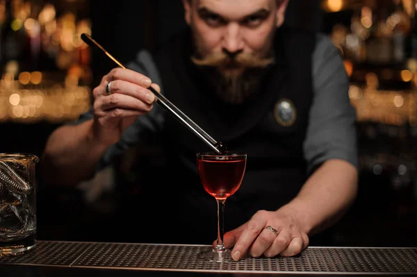 Barman ajoutant un décor avec une pince à épiler au verre — Photo