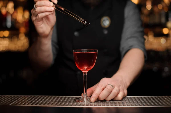 Barista maschio aggiungendo una bacca rossa con pinzette al cocktail — Foto Stock