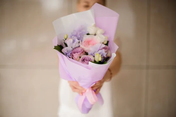 Mulher segurando um buquê de primavera de rosas tenras violetas e rosa — Fotografia de Stock