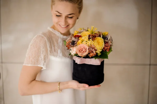 Chica sosteniendo una caja de terciopelo negro de flores amarillas y rosas — Foto de Stock