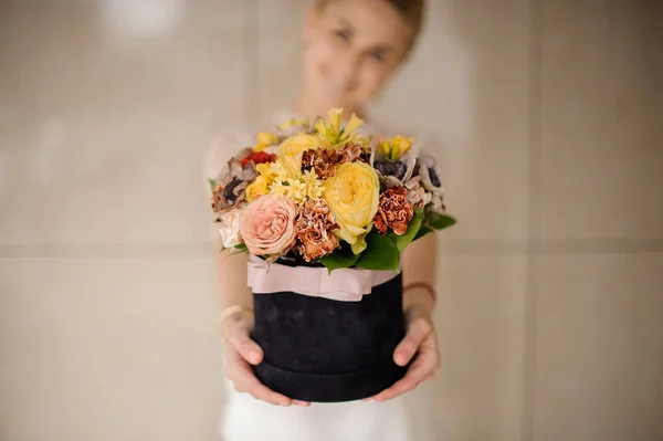 Vrouw met een zwarte fluwelen doos met gele en roze bloemen — Stockfoto