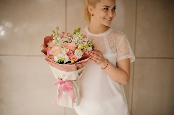 Mujer sonriente sosteniendo un ramo de tiernas flores de primavera rosadas y blancas — Foto de Stock