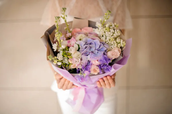 Woman holding a bouquet of tender light color violet spring flowers — Stock Photo, Image
