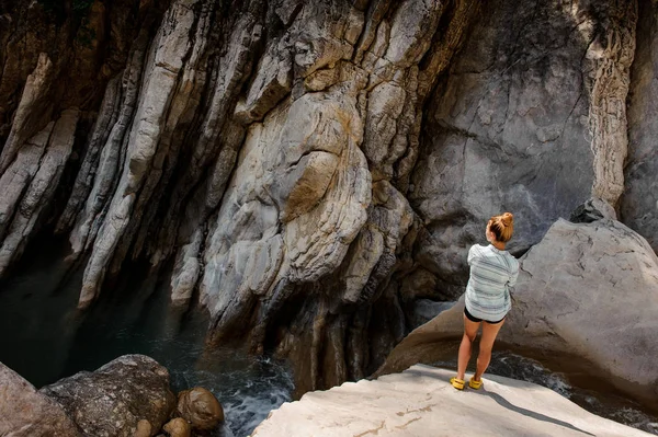 Girl with ponytail standing near waterfall in canyon — Stock Photo, Image