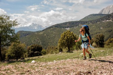 Kadın backpacker tepelerde yolda aşağı seyahat