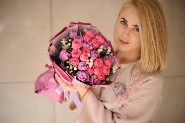 Mor menekşe ve pembe çiçeklerbir buket tutan ceket kız