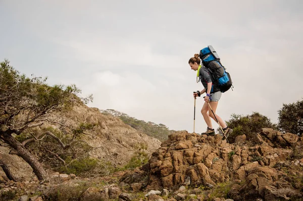 Ragazza che cammina sulle rocce con zaino da trekking — Foto Stock