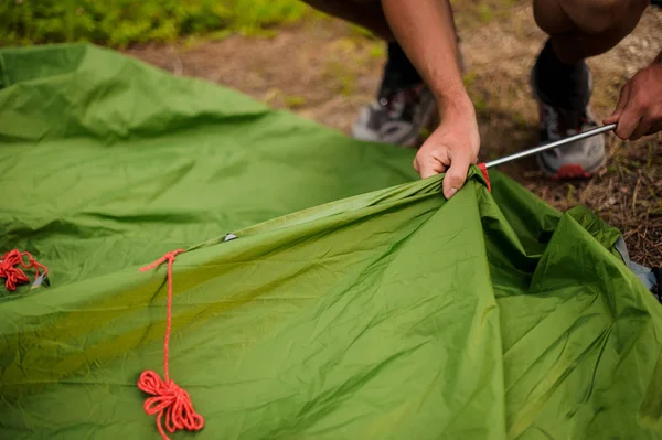 Mann baut ein grünes Zelt auf und steckt es in ein Metallgestell — Stockfoto