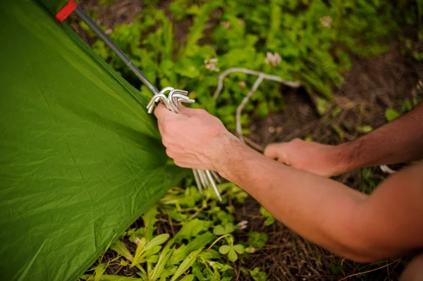 Junger Mann baut grünes Zelt in der Natur auf — Stockfoto