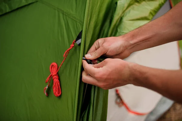 Homem monta uma tenda verde na natureza — Fotografia de Stock