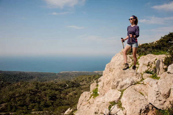 Sportief meisje staande op de rots in shorts met wandelstokken — Stockfoto