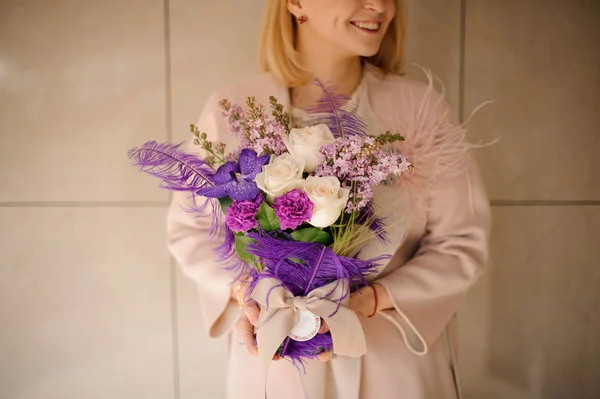 Fille souriante tenant un bouquet de printemps de fleurs roses et violettes tendres — Photo