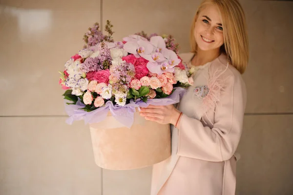 Menina sorridente segurando uma enorme caixa de primavera de flores rosa multicoloridas concurso — Fotografia de Stock