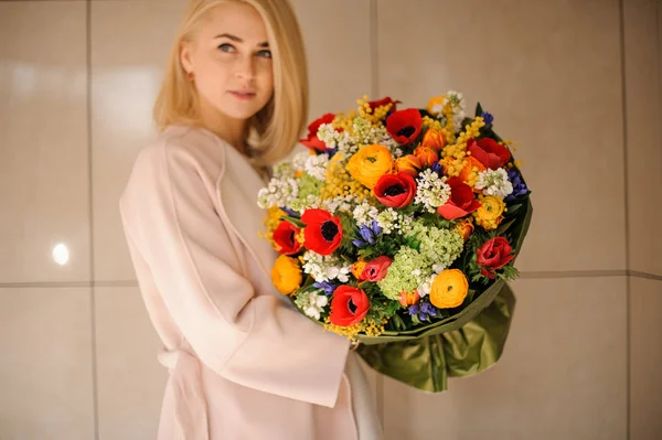 Mujer sosteniendo un ramo de primavera de flores multicolores — Foto de Stock