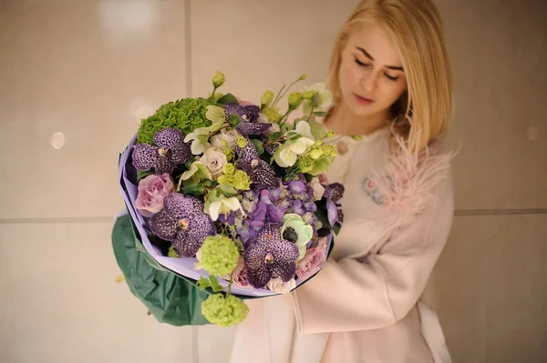 Femme tenant un bouquet de fleurs violettes et vertes — Photo