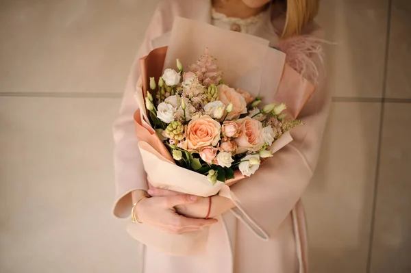 Girl in the coat holding a bouquet of creamy color and white flowers — Stock Photo, Image