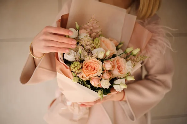 Frau im Mantel mit einem Strauß cremiger Farbe und weißen Blumen — Stockfoto