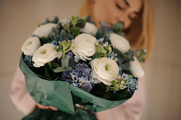 穿着外套的女人拿着一束娇嫩的白花和深蓝色的花 — 图库照片