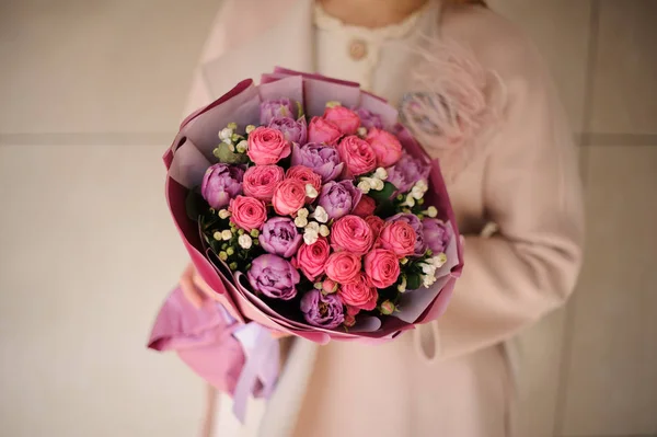 Woman in the coat holding a bouquet of purple violet and pink flowers — 스톡 사진