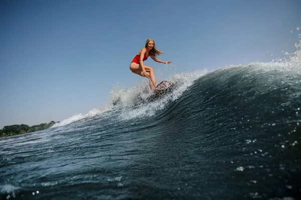 Woman with loose hair surfs in sea