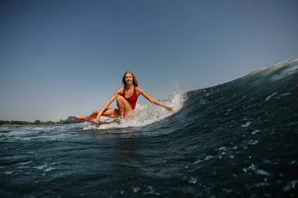 Woman with loose hair surfs in a sea