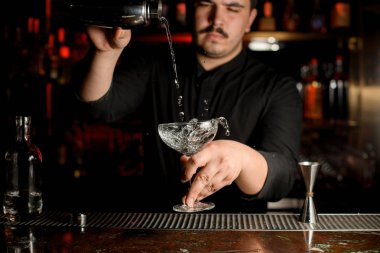 Barmen çelik shaker gelen kokteyl cam içine şeffaf bir alkol döküyor