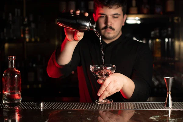 Profissional bartender masculino derramando um álcool transparente no copo de coquetel da coqueteleira de aço — Fotografia de Stock