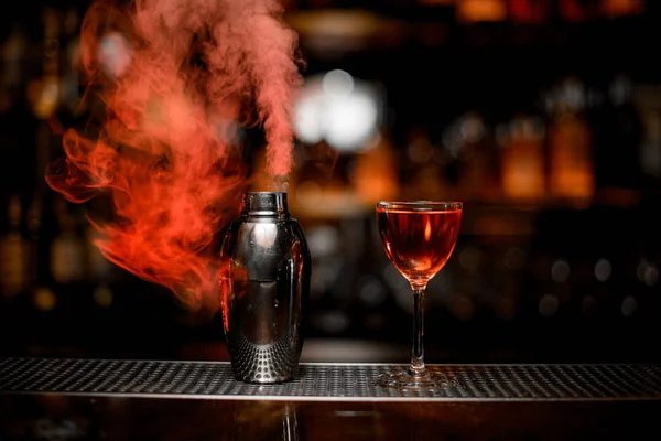 Cocktail in the glass and smoky steel shaker — Stock Photo, Image
