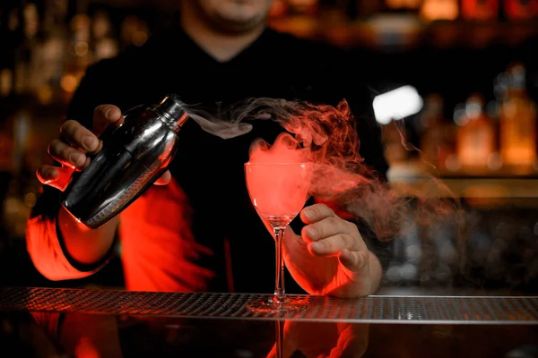 Cantinero profesional echando humo en la copa de cóctel de la coctelera — Foto de Stock