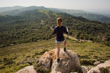 Geri görünümü kız baston ile şort kaya üzerinde duran