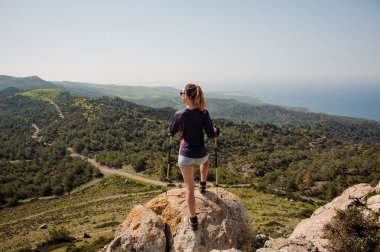 Geri görünüm sportif kız baston ile şort kaya üzerinde duran