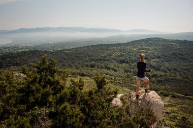 Geri görünüm genç kız baston ile şort kaya üzerinde duran