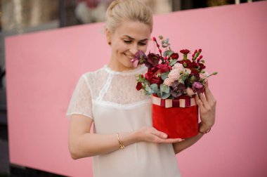 Gülümseyen kız şapka kutusunda buket tutun