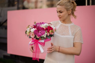 Kız yay ile şapka kutusunda irises ile buket tutar