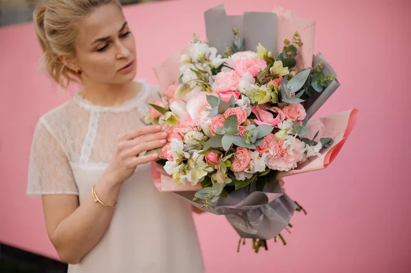 Young girl holds bouquet in gray and pink paper — 스톡 사진