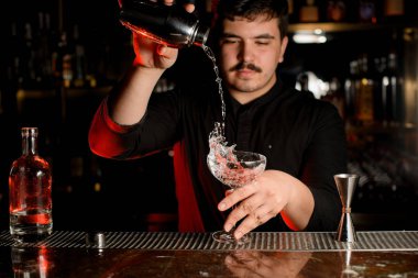 Barmen shaker ile bir alkol içeceği döker