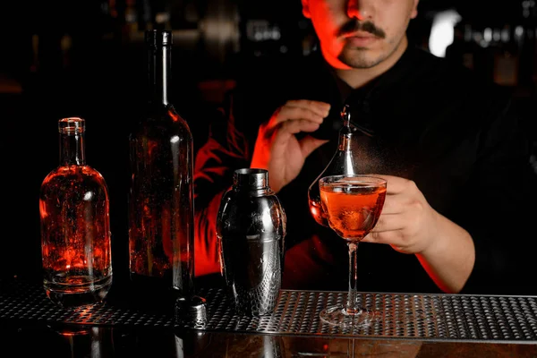 Nahaufnahme von Flaschen, Shaker, Cocktail und Barkeeper mit Sprüher — Stockfoto