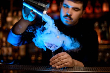 Barmen bir alkol kokteyli dökmek için shaker kullanarak
