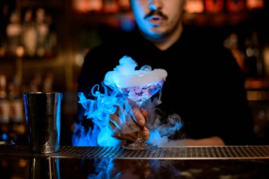 Barmen bir alkol kokteyli karıştırmak için shaker kullanarak