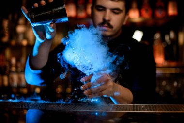 Barmen bir alkol içeceği karıştırmak için shaker kullanır