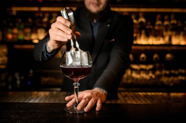 Barmen bir kokteyl büyük buz küpü ekler