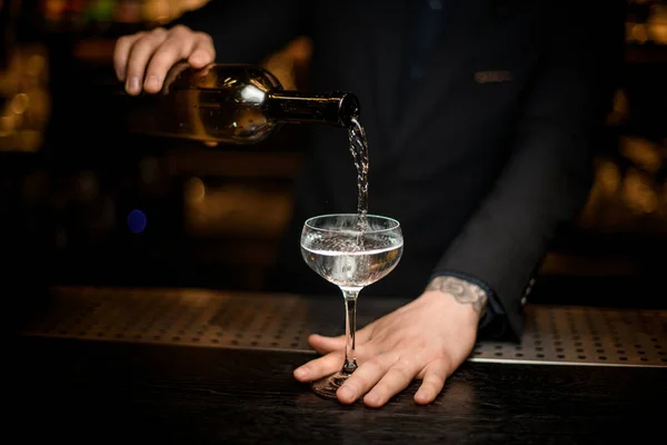 Barman masculino adiciona champanhe em um copo — Fotografia de Stock