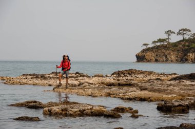Sırt çantası olan kadın deniz kıyısında seyahat ediyor
