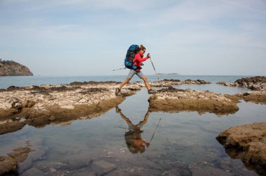 Sırt çantası ile kadın bir deniz kıyısında treks