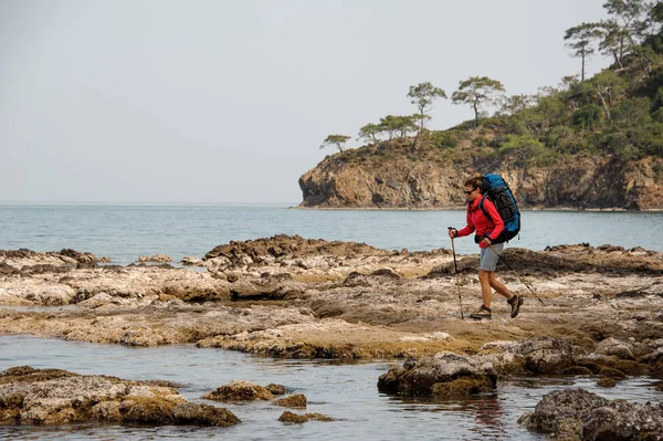 Woman with backpack hiking on a sea coast