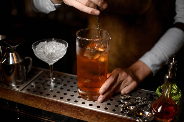 Bartender omrörning en läcker brun cocktail i mäta glas kopp — Stockfoto