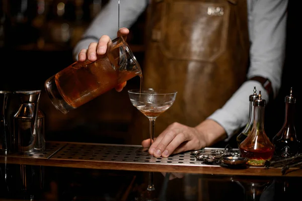 Bartender hälla en alkoholhaltig dryck från mätglaset till cocktailglas — Stockfoto