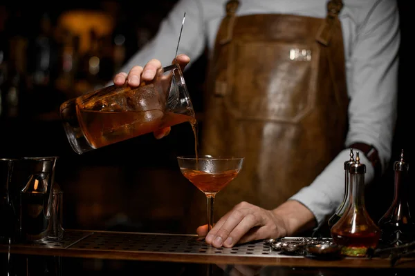 남성 바텐더가 측정 컵에서 칵테일 잔까지 알코올 음료를 부은다. — 스톡 사진