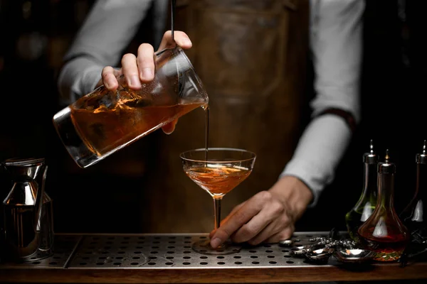 Barman derramando um coquetel alcoólico marrom do copo de medição para o copo — Fotografia de Stock