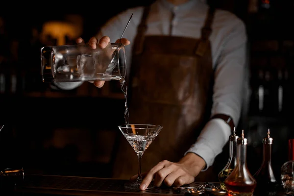 Manlig bartender hälla en alkoholhaltig dryck från mätglaset till martini glas — Stockfoto